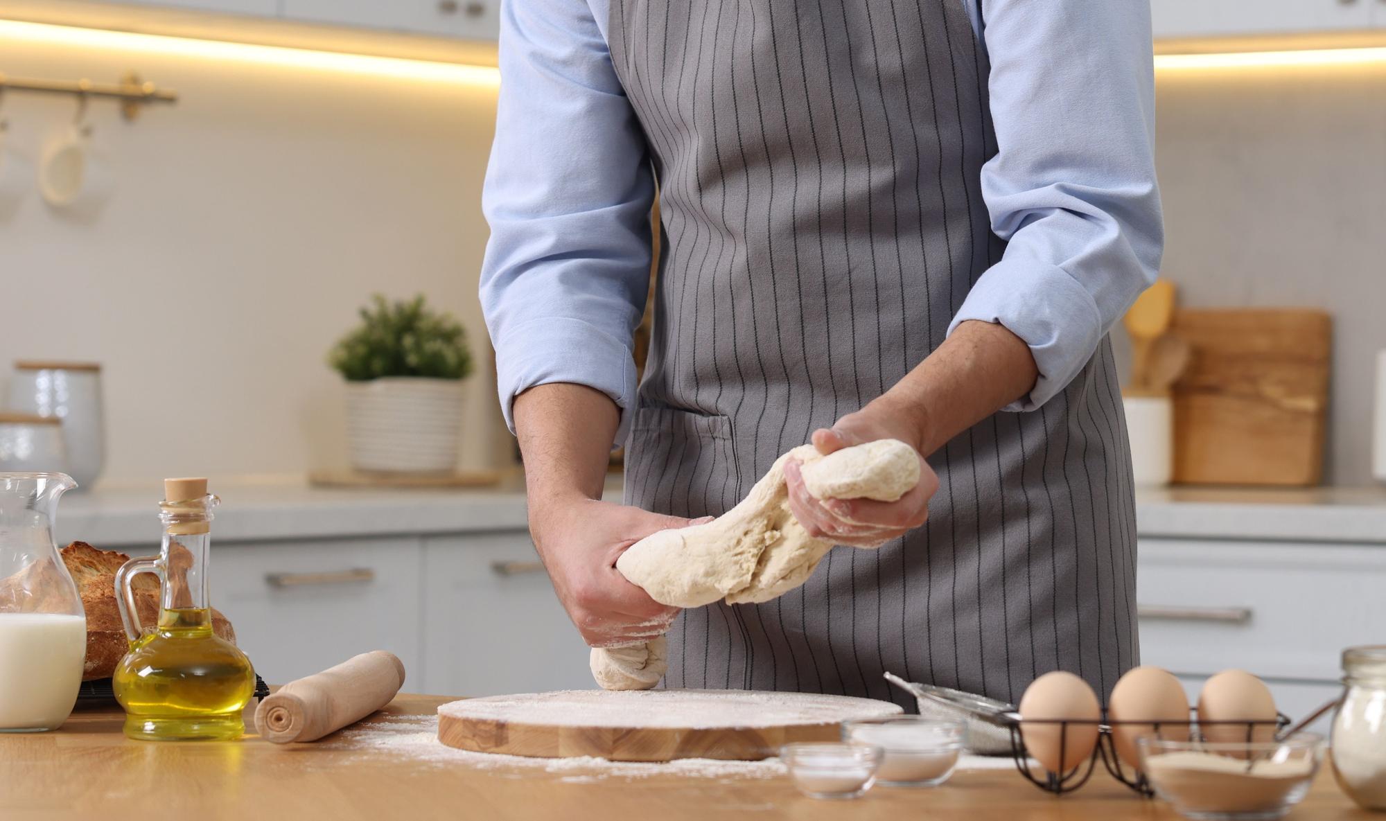 Chef hands kneading dough on wooden board
